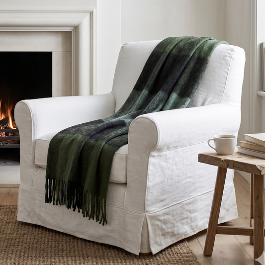 White armchair with a green blanket in front of a fireplace in a cozy living room.