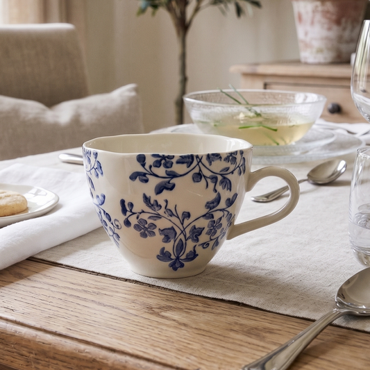 Dining table setting with a blue and white floral mug, cookies, and glasses.