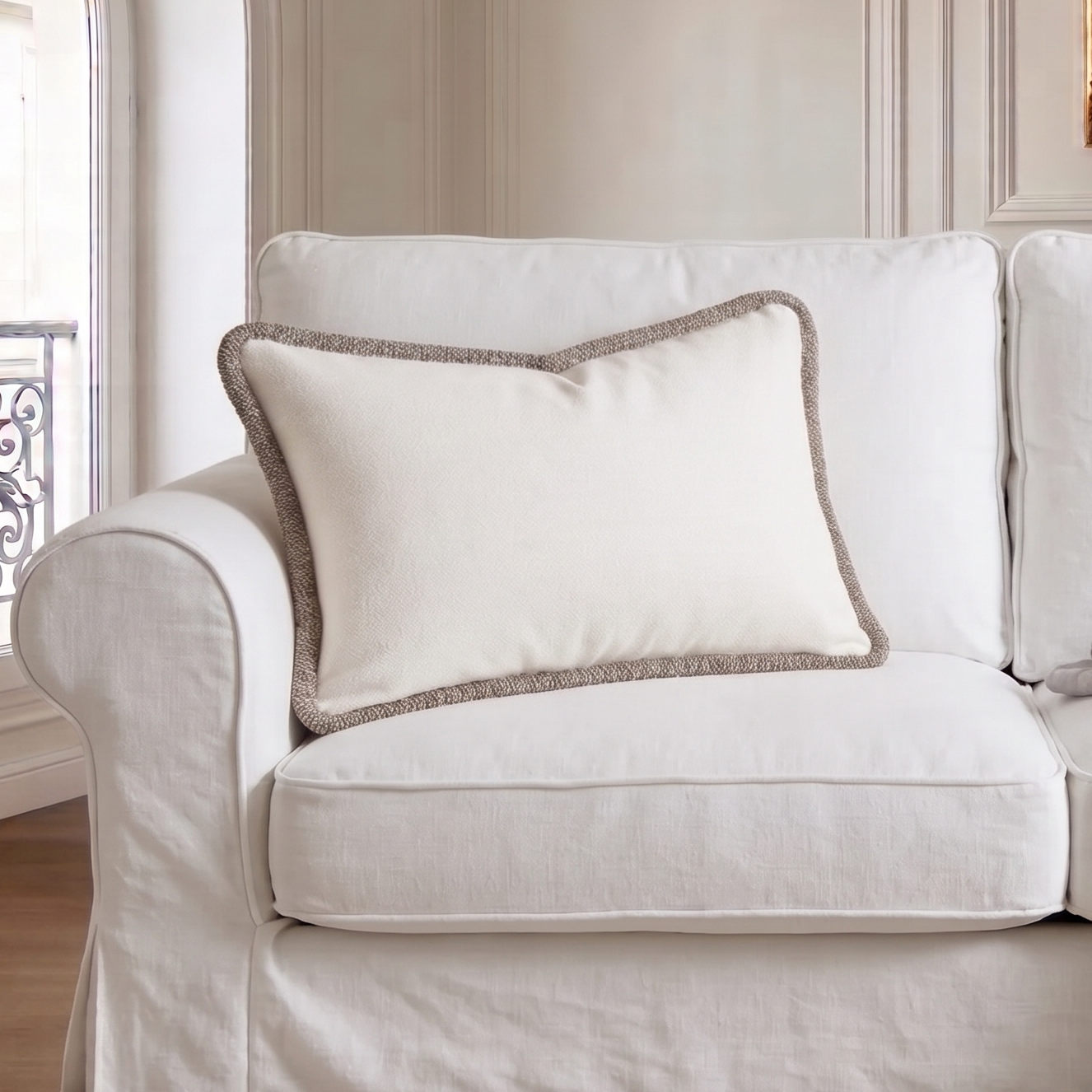 White sofa with a decorative pillow and blanket in a stylish room.