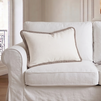White sofa with a decorative pillow and blanket in a stylish room.