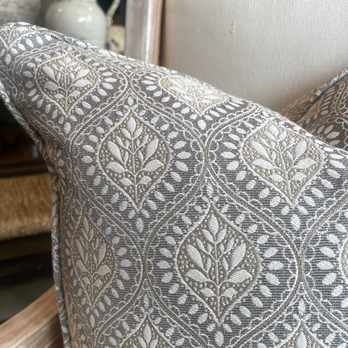 This distinguished heavyweight Geometric Taupe Grey Cushion, boasting a refined geometric pattern crafted by esteemed fabric house Warwick Fabrics, brings a touch of elegance to any environment. Merging subtle neutral tones, the cushion is complete with a plush feather insert for maximum comfort. Corner close up.