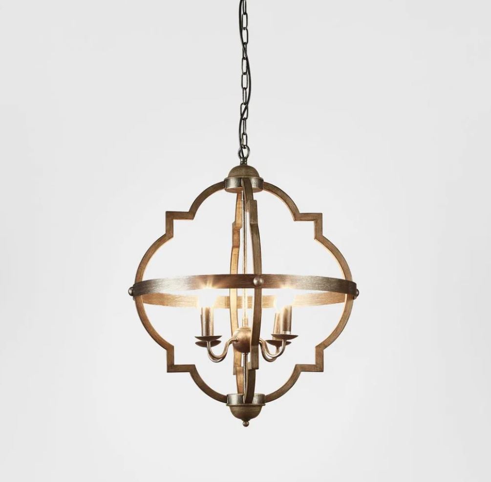 A hanging pendant light fixture with a distressed bronze metal frame, featuring a quatrefoil-style outer border and a central ring with candle-style bulbs, shown against a plain light gray background.