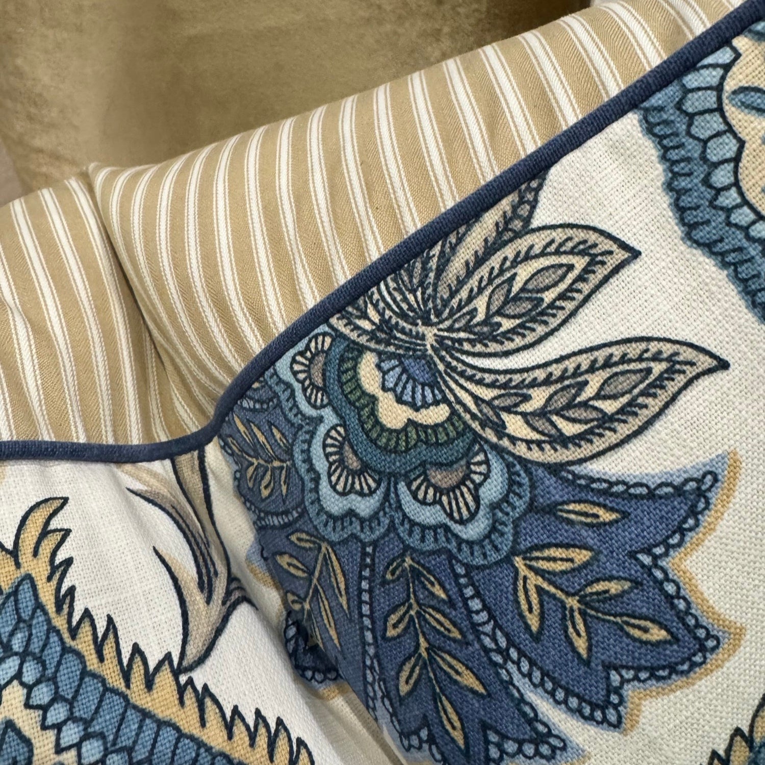 Elevate your interior with the Emily Blue &amp; Taupe Floral Cushion, masterfully crafted using superior fabrics. The sophisticated floral pattern displays captivating blue and taupe hues on a pristine ivory canvas, drawing admiring glances in any setting. Flip to reveal a refined ochre ticking stripe complemented by rich deep blue piping for versatile styling options. 