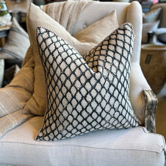 Decorative pillow with geometric pattern on a beige armchair in a home setting