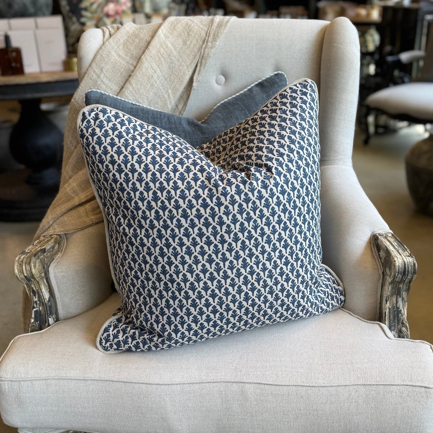 Decorative pillow on an ornate chair in a store setting