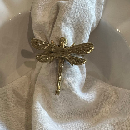 Gold dragonfly-shaped napkin ring on a white napkin