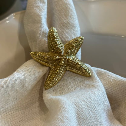 Gold starfish-shaped napkin ring on a white napkin