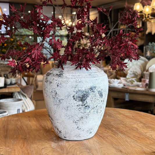 Decorative vase with red branches on a wooden table in a store setting