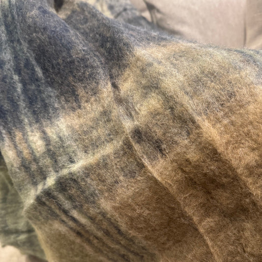 Close-up of a textured blanket with earthy tones on a couch.