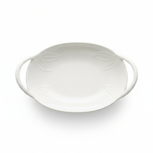 An oval white ceramic serving dish with two side handles and embossed leaf details,