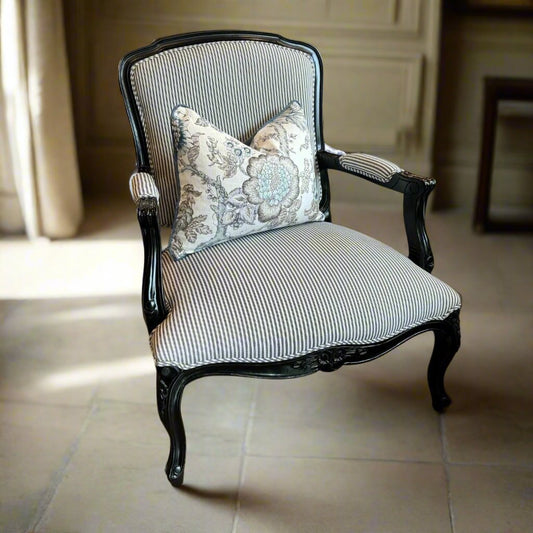 Indulge in timeless French style with this elegant armchair, exquisitely crafted from sturdy mahogany and finished with a sleek black gloss. Its luxurious hand-carved details and sturdy frame add a touch of sophistication to any living room or bedroom, while the stunning blue and white ticking fabric upholstery adds a subtle yet eye-catching touch. Elevate your space with this expertly crafted piece that exudes elegance and charm.