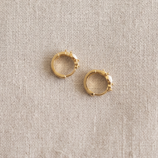 Pair of gold hoop earrings on a beige fabric background