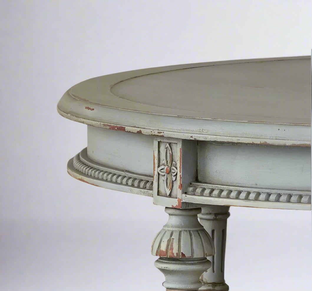 Round distressed table with decorative legs on a white background