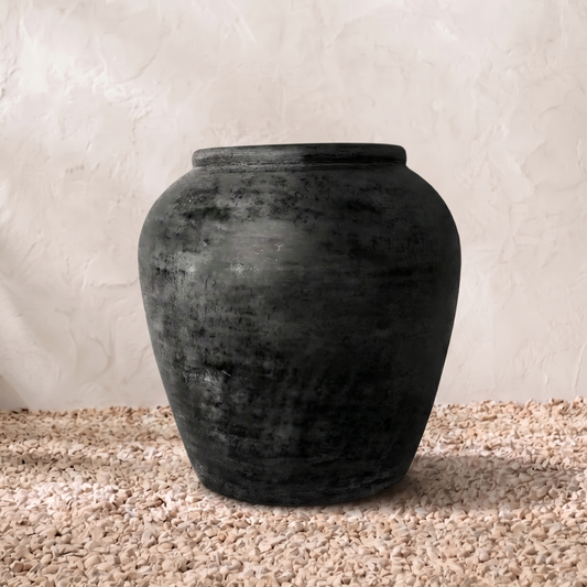 Dark grey terracotta vase on a textured surface with a neutral background