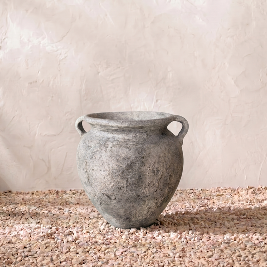 Gray terracotta pot on a textured surface with a light background