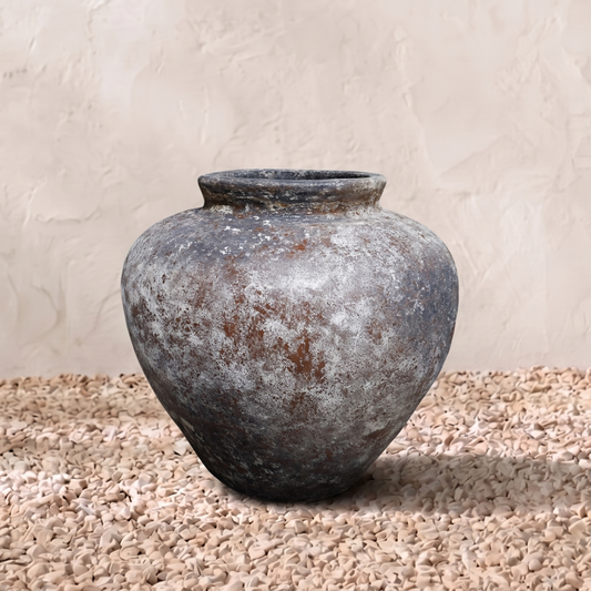 Vintage-style terracotta pot on a textured surface with a neutral background