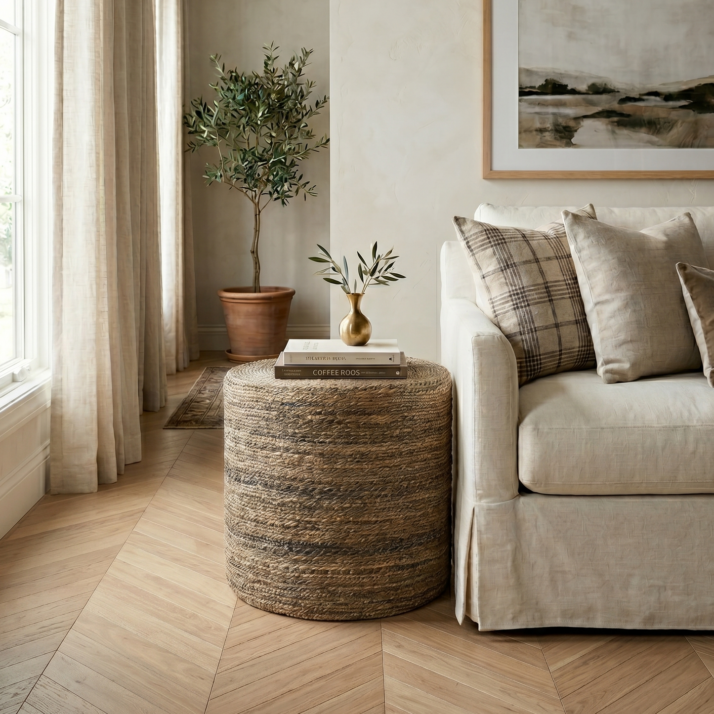 Living room with beige sofa, woven ottoman, and framed artwork.