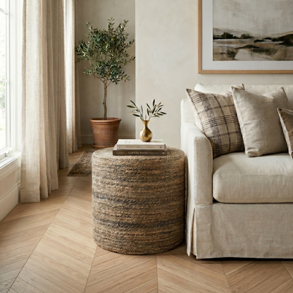 Living room with beige sofa, woven ottoman, and framed artwork.