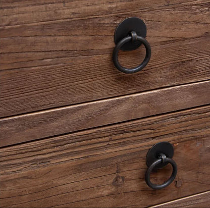 Two round black metal ring pulls mounted on a rustic brown wooden drawer front.