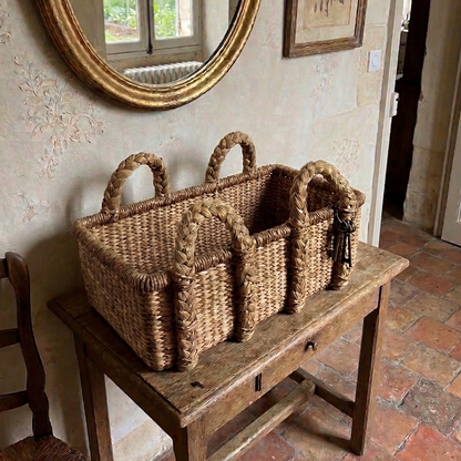 Water hyacinth basket on a wooden bench in a room with a large round mirror and framed picture.