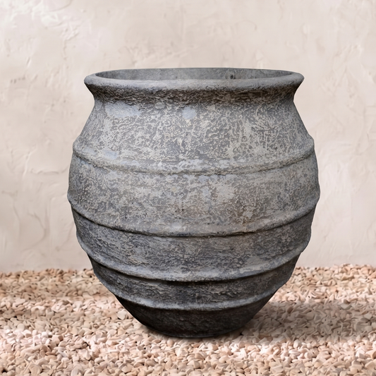 Decorative stone vase on a textured surface with a neutral background