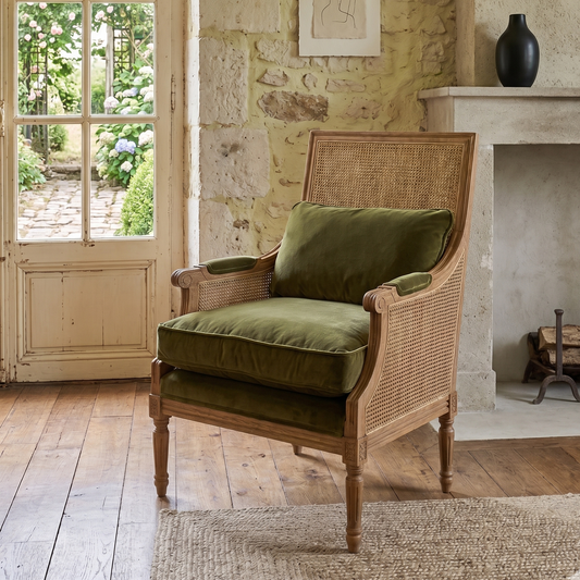 Wooden armchair with green cushions in a room with stone walls and a fireplace.