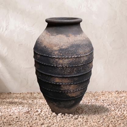 Terracotta pot with layered design on a textured surface