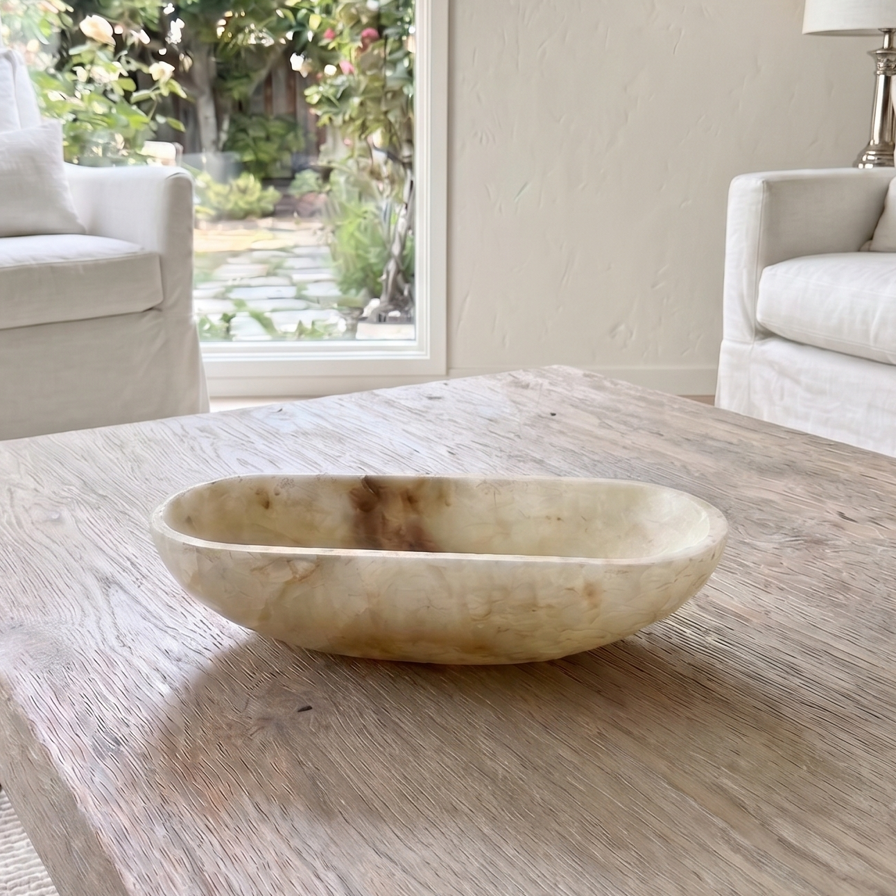 Decorative bowl on a wooden table with a blurred garden and chairs in the background