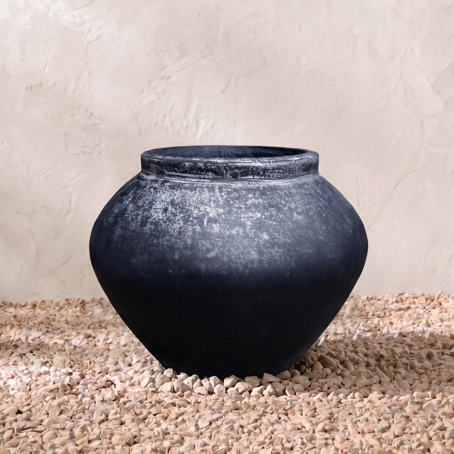 Black ceramic vase on a textured surface with a neutral background