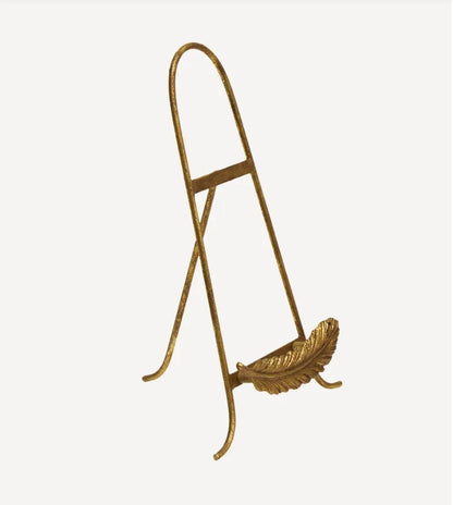 A gold-finished metal decorative stand shaped like a folding easel with a leaf-shaped base, shown against a plain light gray background.