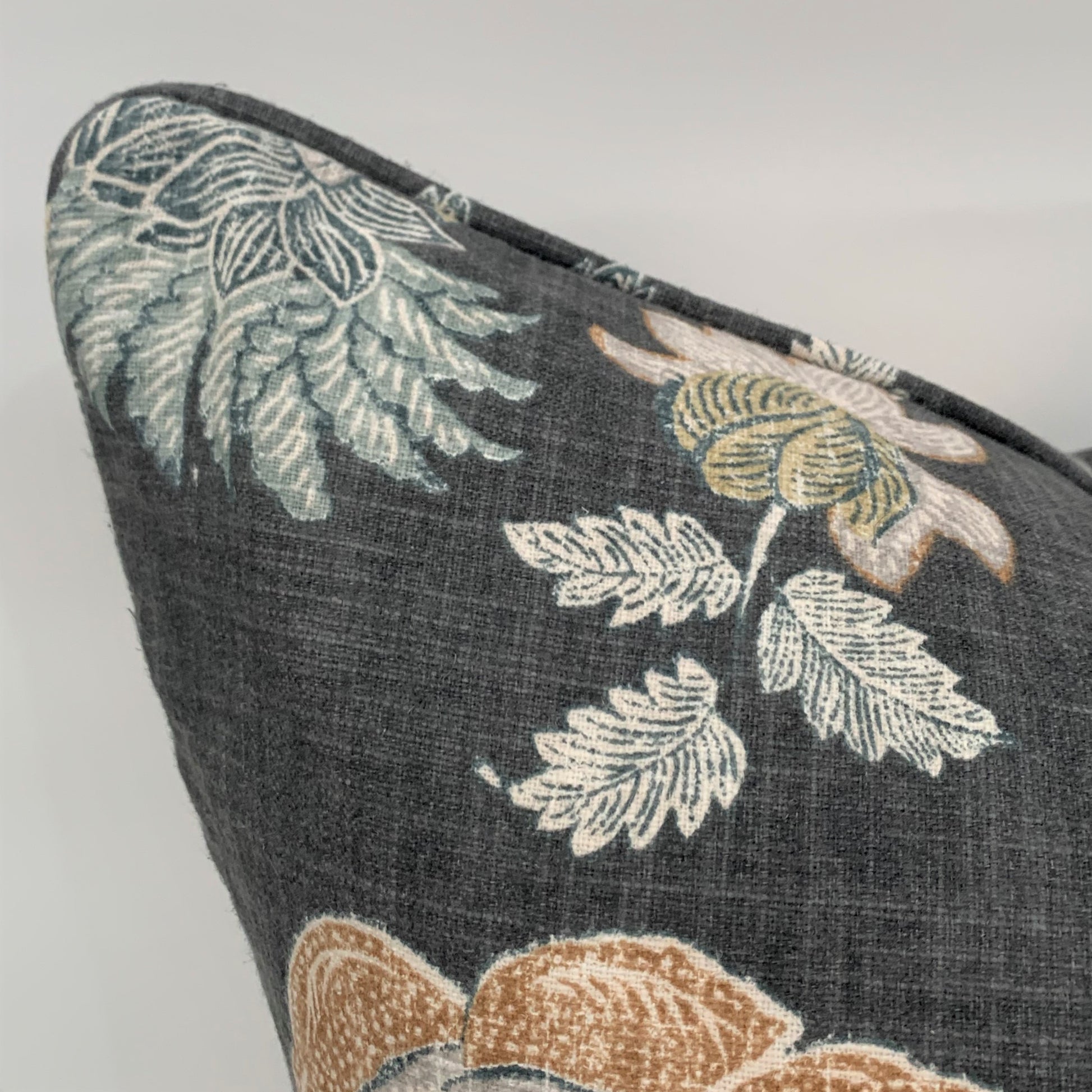 This beautiful Graphite Floral Linen Cushion from Richloom Fabrics is exquisitely crafted from a sumptuous heavyweight fabric. With a soft floral pattern and subtle hues against a dark grey backdrop, it adds a timelessly graceful and elegant touch to any home decor. Includes a luxurious feather insert. Close up corner.