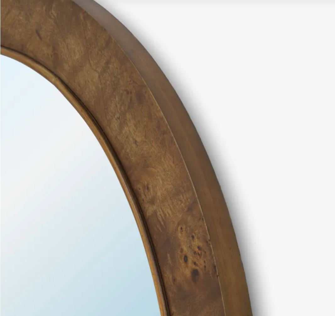 Close-up of a round mirror with a thick, textured burl wood frame in a warm golden-brown finish, set against a plain white background.
