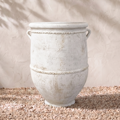 Decorative stone planter on a sandy surface with a neutral background
