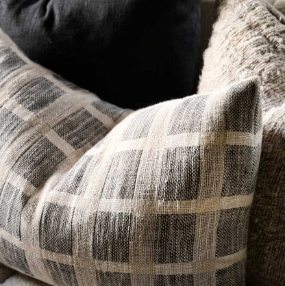 An embodiment of understated elegance, the Chloe Criss-Cross Taupe Linen Cushion is inspired by the cobbles stones of Greece, featuring a luxe weave that captures the eye. Add the matching throw and other pieces from our collection to create a beautiful ensemble, or let the cushion stand on its own. Filled with the exclusive, ultra-comfortable plump feather insert , crafted from linen/cotton yarn dyed check and is OEKO-TEX® and GOTS certified. Close up corner.