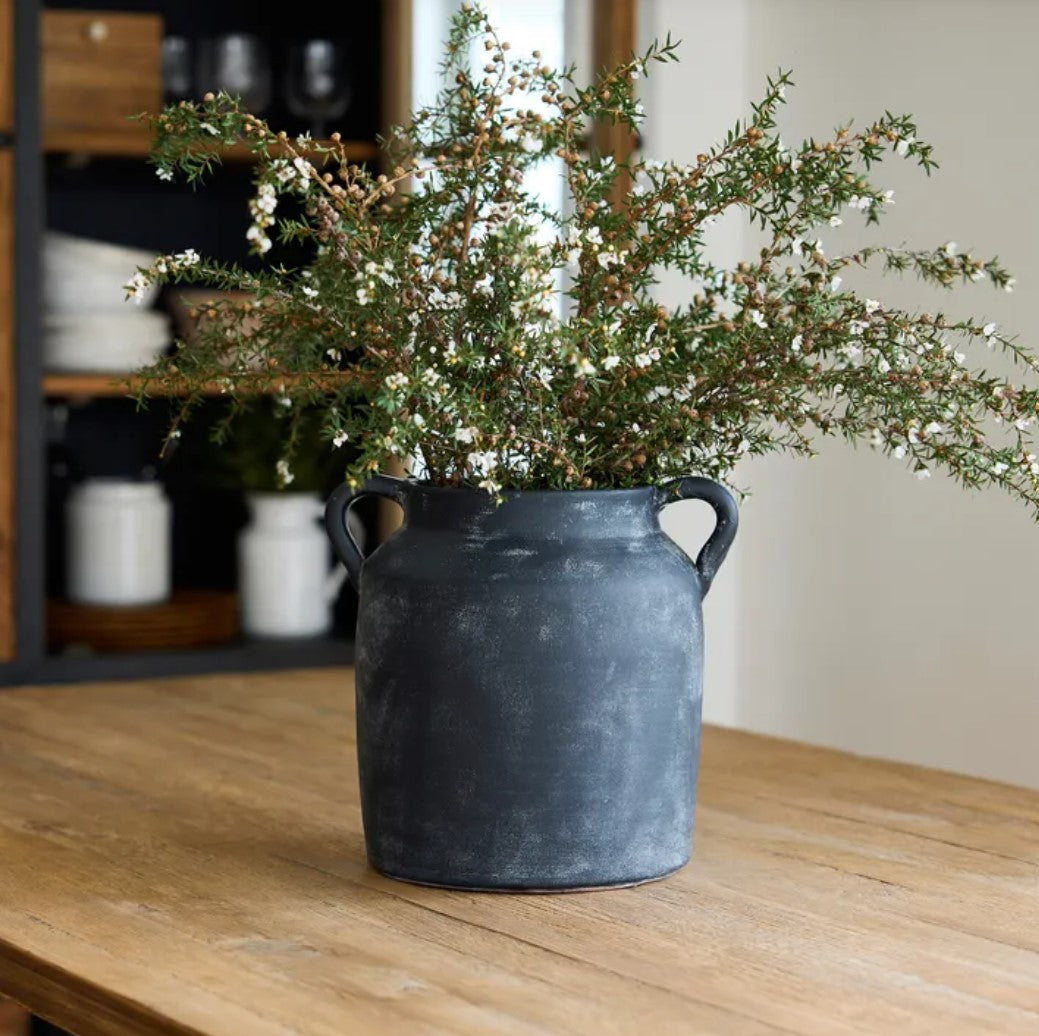 Transform your space with this Oliver Black Distressed Terracotta Pot, featuring a timeless and rustic charm that exudes character and elegance. The black and white distressed finish and small handles make it perfect for styling on a coffee table, shelf, or table. Get ready to add a touch of sophistication to your home!