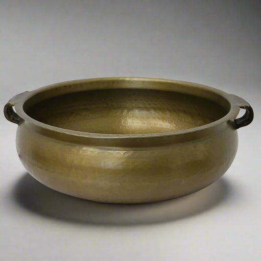 This Basque Bowl features handles and a hammered antique brass finish, crafted from aluminium. It serves as a striking table centrepiece or a bold statement piece for your home.