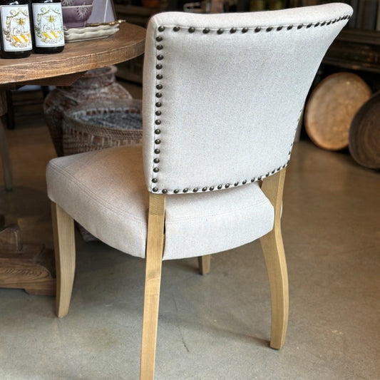 The Chelsea Dining Chair is constructed with a cream linen finish and features stud detailing on the back for a sophisticated, yet comfortable aesthetic. Back.