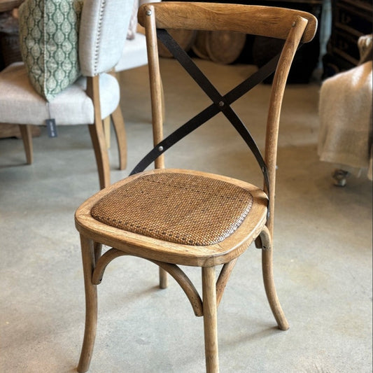 Fashioned with a sturdily crafted Oak frame and adorned with aged metal straps, the Lyon Crossback Chair features a rattan seat to enhance its visual aesthetic.