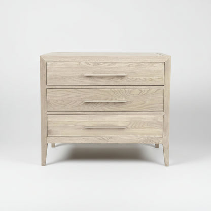 Wooden nightstand with three drawers on a light gray background