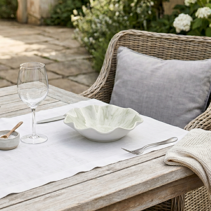 Outdoor dining setup with a wooden table, wicker chair, and garden view.