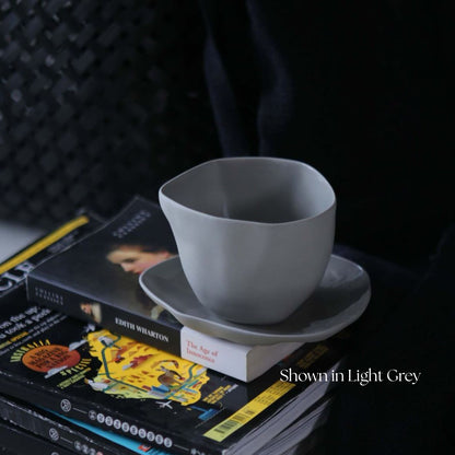 Gray ceramic cup and saucer on a stack of books with a dark background