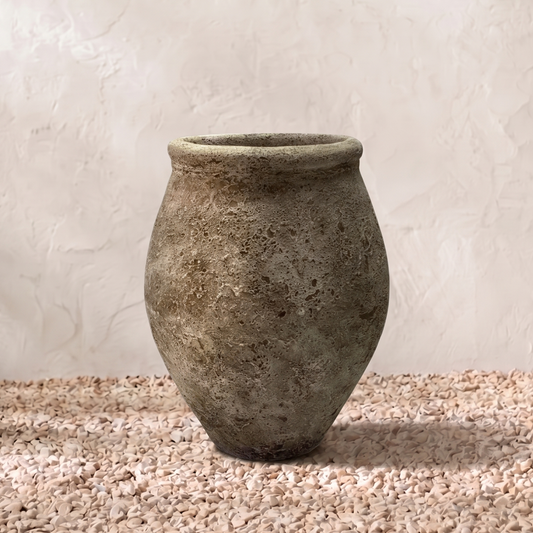 Vintage stone vase on a textured surface with a neutral background