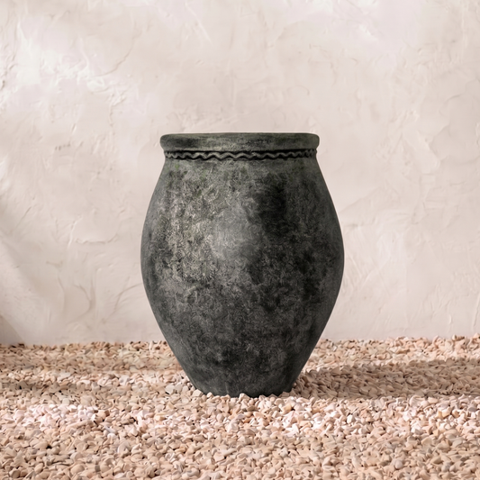 Black stone vase on a textured surface with a light background