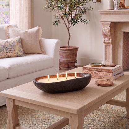 Living room with a wooden coffee table, candle, books, and a fireplace.