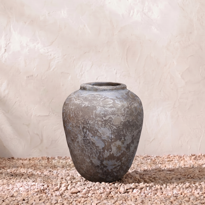 Vintage-style terracotta pot on a textured surface with a neutral background