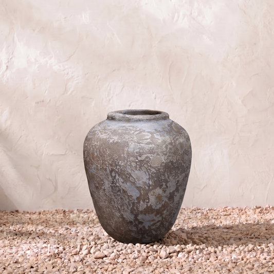 Vintage-style terracotta pot on a textured surface with a neutral background