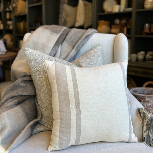 The Jambi Handwoven Cotton Beige Cushion is made from high-quality cotton, giving it a natural texture. Adorned with beautiful taupe stripes, it effortlessly complements any room and style with its muted beige tones. Styled.