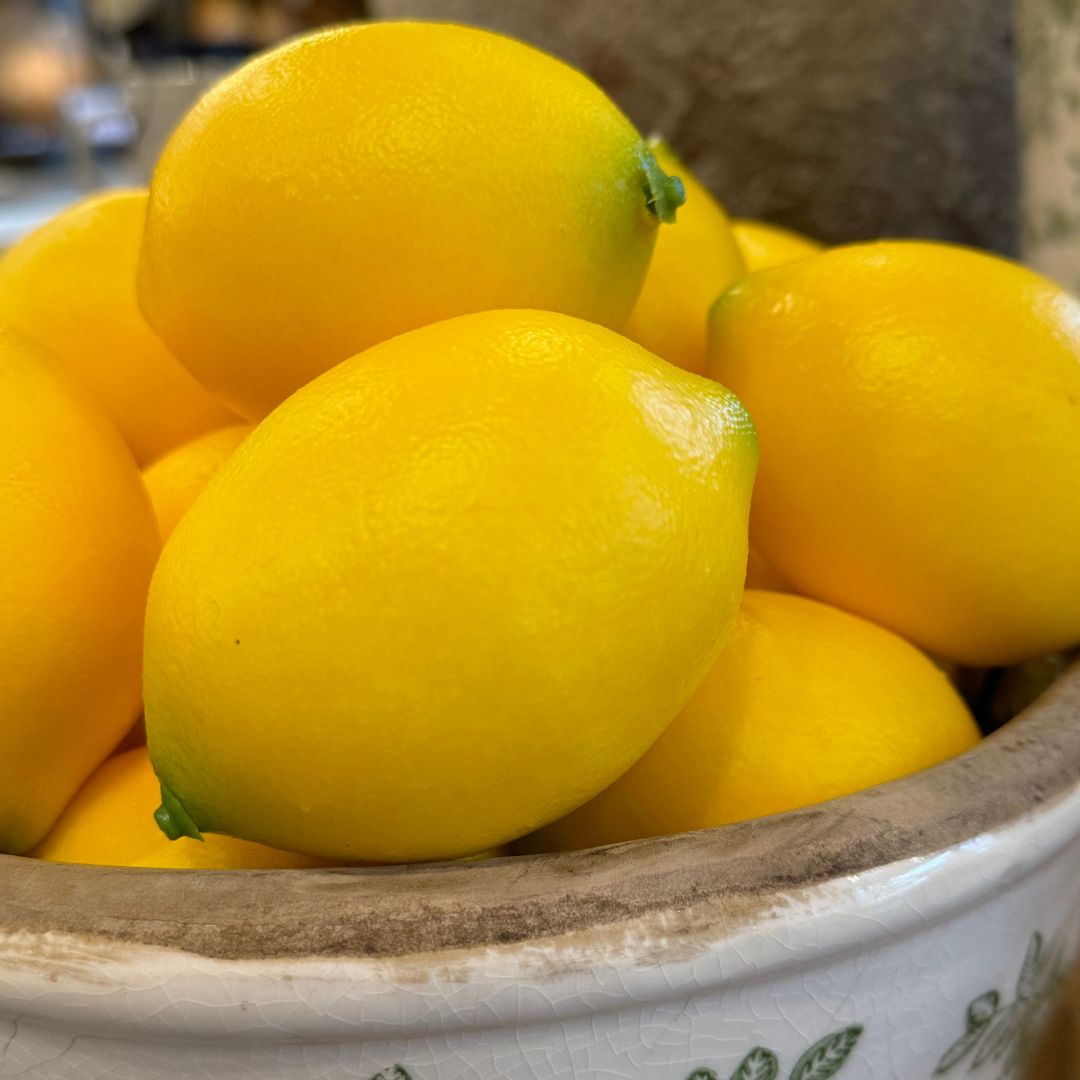 The vibrant Faux Lemon is the perfect option for crafting captivating decorations. Its striking burst of yellow adds a distinctive touch and texture, making it ideal for featuring alone in a bowl or as part of a larger display. Detail.