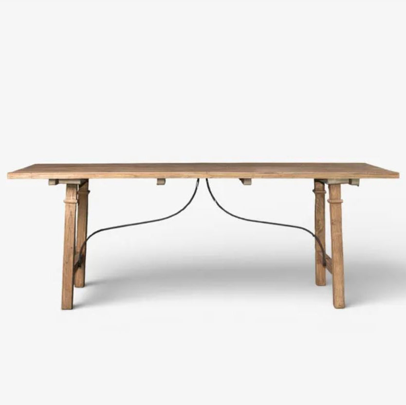 A light natural wood dining table with a rectangular top and four tapered legs, supported by a curved black metal base bar, shown against a plain white background.