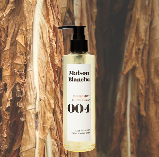 Maison Blanche hand wash bottle with a label against a textured brown background